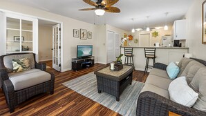 Ein Wohnzimmer mit Rattanmöbeln, einem Deckenventilator und einem Fernseher.