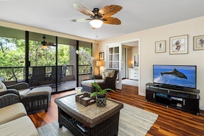 Relax in a stylish living room with a large flat-screen TV, wicker sofas, and a coffee table.