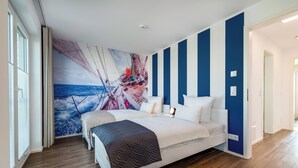 A bedroom with a large bed, a nautical-themed wall mural, and a view of the ocean through the window. - Vacation home Backbord with roof terrace, directly on the water with Baltic Sea & Schlei view (Kappeln)