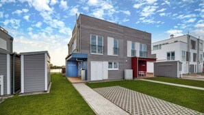A modern residential building with a covered outdoor area, a pathway, and a small lawn. - Vacation home Backbord with roof terrace, directly on the water with Baltic Sea & Schlei view (Kappeln)
