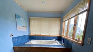 Une cuisine compacte dotée d’une baignoire intégrée, d’un escalier en bois et d’une fenêtre avec des stores.