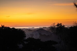 A sunset view with a house silhouette and surrounding trees.