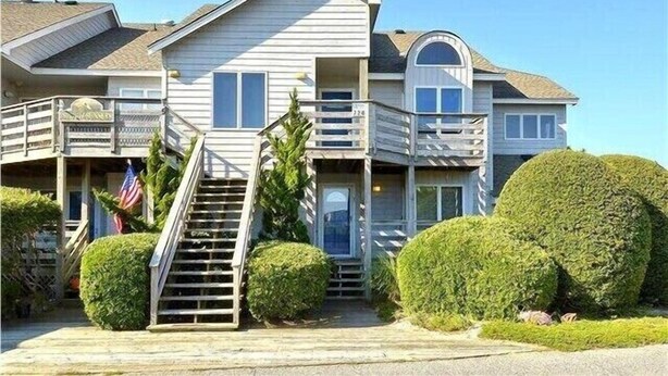 Une maison à deux étages dotée d’un balcon, d’un porche à l’avant et d’un escalier menant à l’entrée.