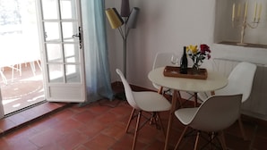 Un comedor con una mesa dispuesta para dos personas, una botella de vino y un jarrón con flores.
