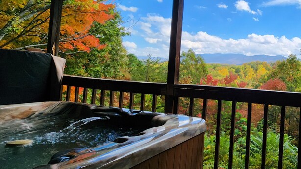 A hot tub under a wooden pergola with a view of autumn foliage and mountains. - McKenzie Cabin: A Cozy Romantic Updated Retreat with Mountain Views and Hot Tub (Sevierville)