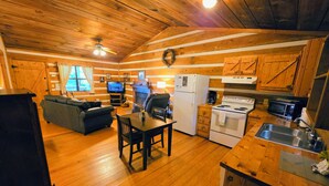 A cozy cabin interior with a living room, dining area, kitchen, and a fireplace. - McKenzie Cabin: A Cozy Romantic Updated Retreat with Mountain Views and Hot Tub (Sevierville)