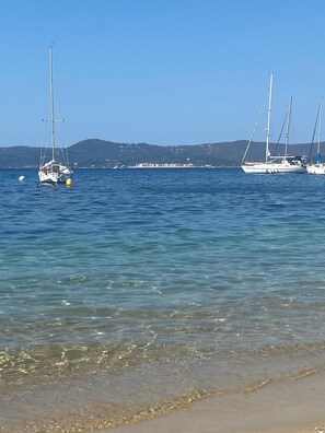 A calm sea with boats anchored near the shore.