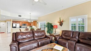 A spacious living room with leather sofas, a dining area, and a kitchen in the background.