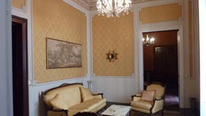 Una habitación con sofá, sillones, una mesa, candelabro, un cuadro y un espejo.