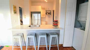 A kitchen with a white countertop, stainless steel appliances, and a hanging pot rack.