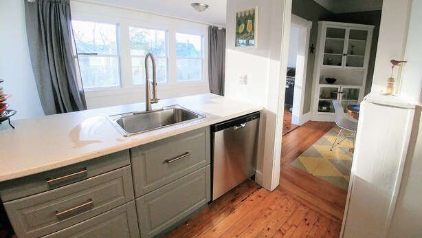 A kitchen with a dishwasher, a sink, and a window with curtains. - Beside The Tulip Tree - 3Bd Historic Home located in Waterfront District (Shelburne)