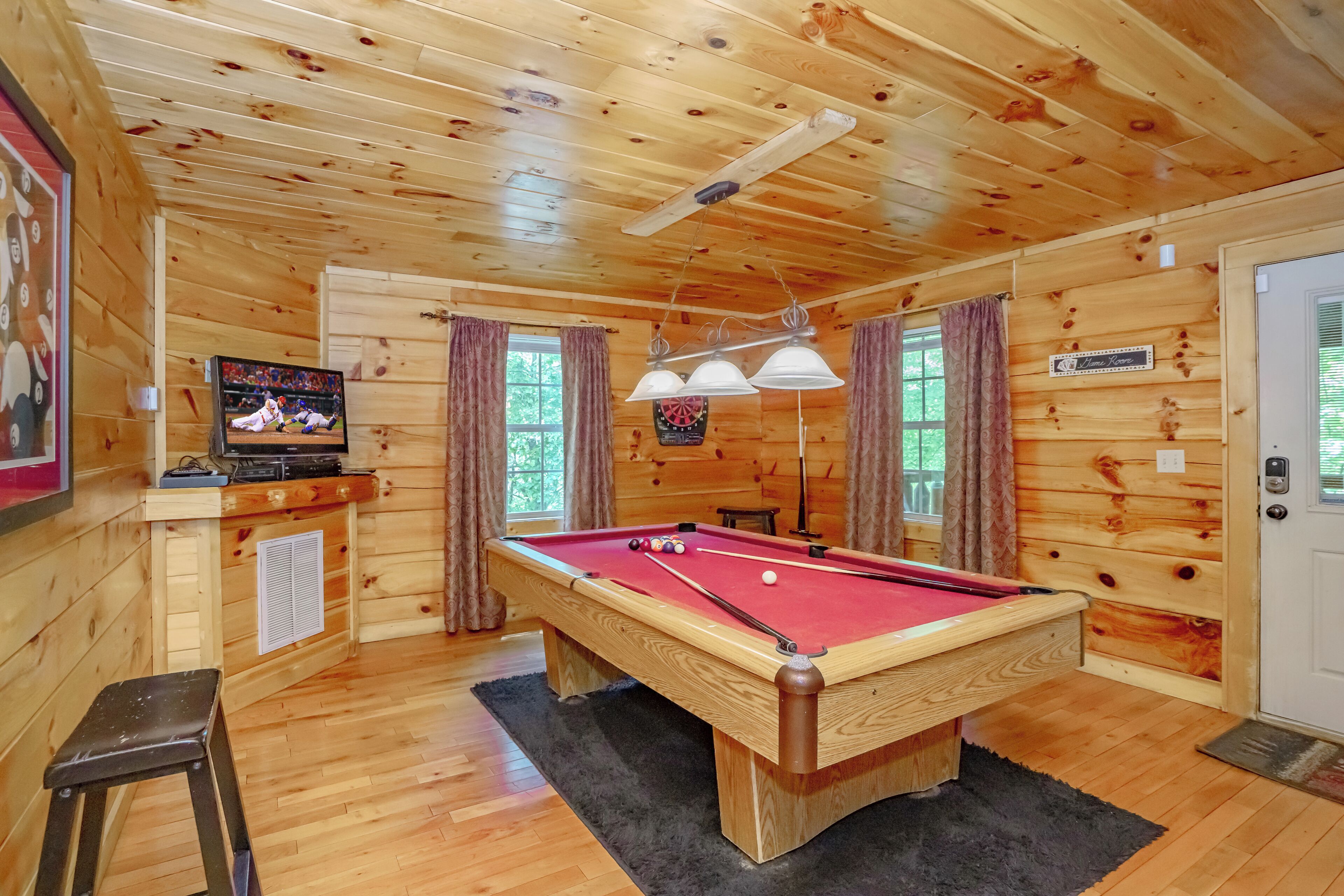 Una mesa de billar en una sala de madera con una televisión, un dardo y un cartel que dice 'Lakeview Room'.