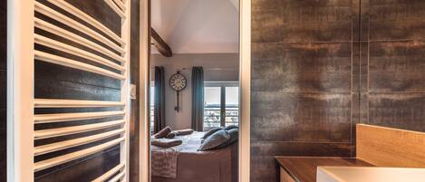 Une chambre à coucher moderne avec un lit, une tête de lit en bois, une table de chevet et une grande fenêtre avec des rideaux.