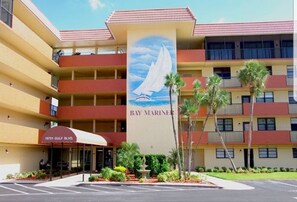 A multi-story hotel with a sailboat mural, balconies, and a parking lot.