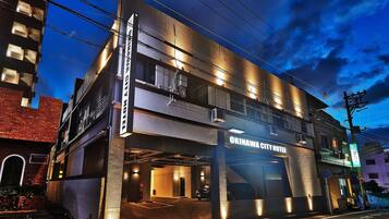 The exterior of Okinawa City Hotel with a modern design, multiple floors, and a parking garage entrance.