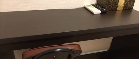 A dark wooden desk with a remote control and a decorative box on top.