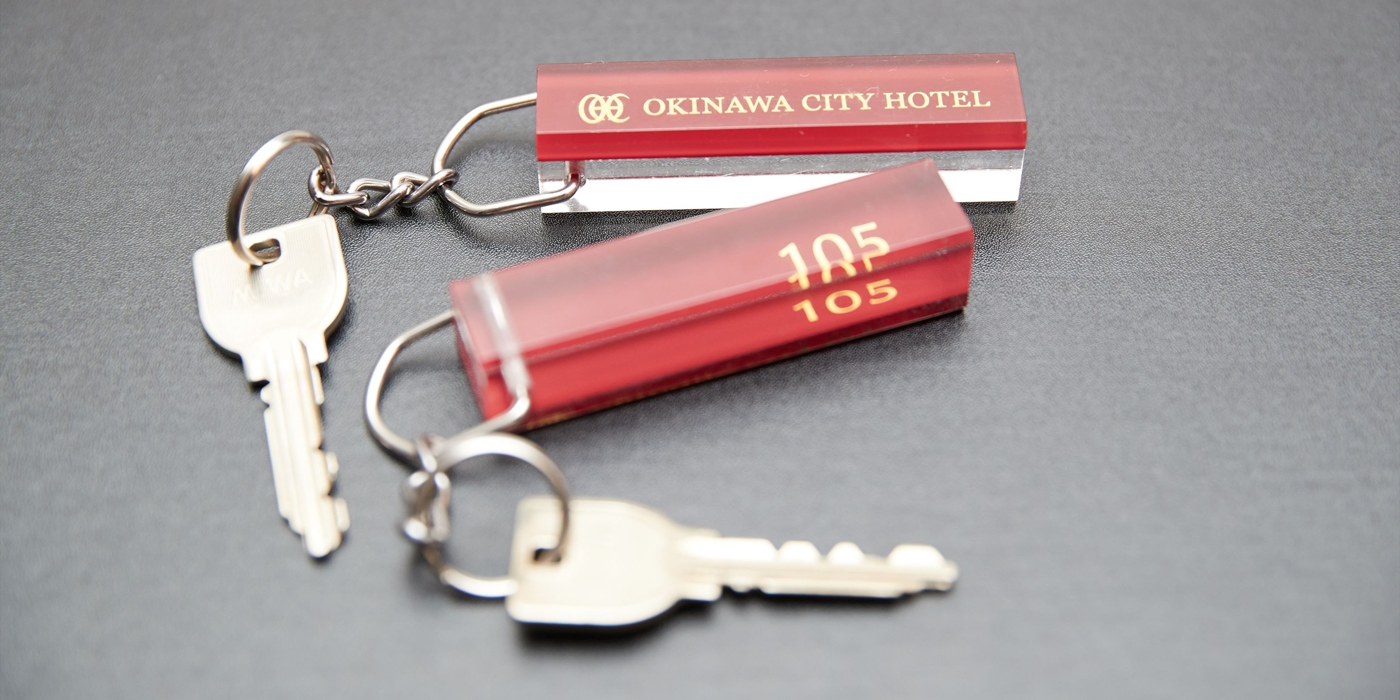 A set of keys and a hotel keychain labeled "OKINAWA CITY HOTEL" and "105".