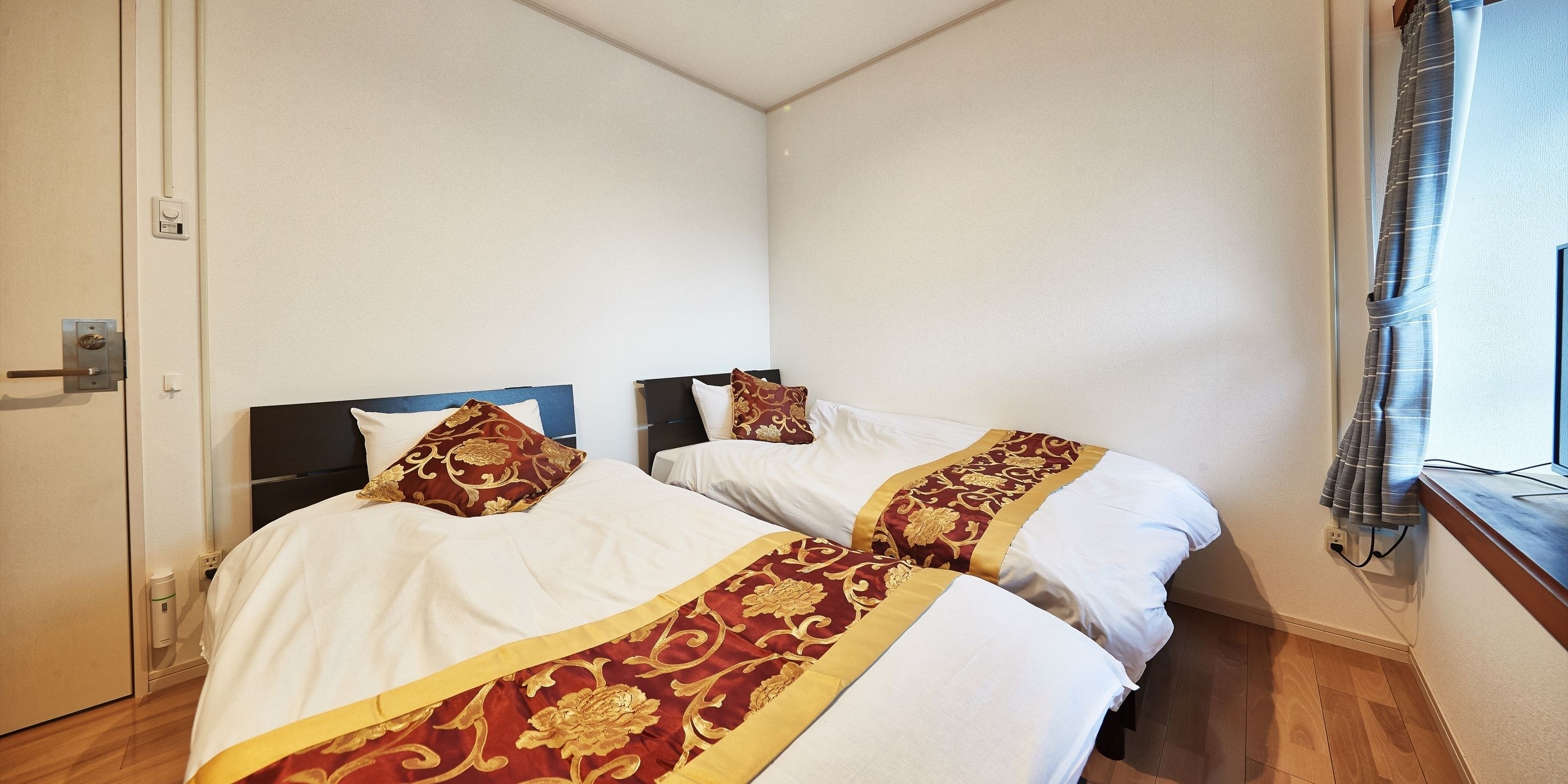 A hotel room with two beds, each with a headboard and decorative pillows.