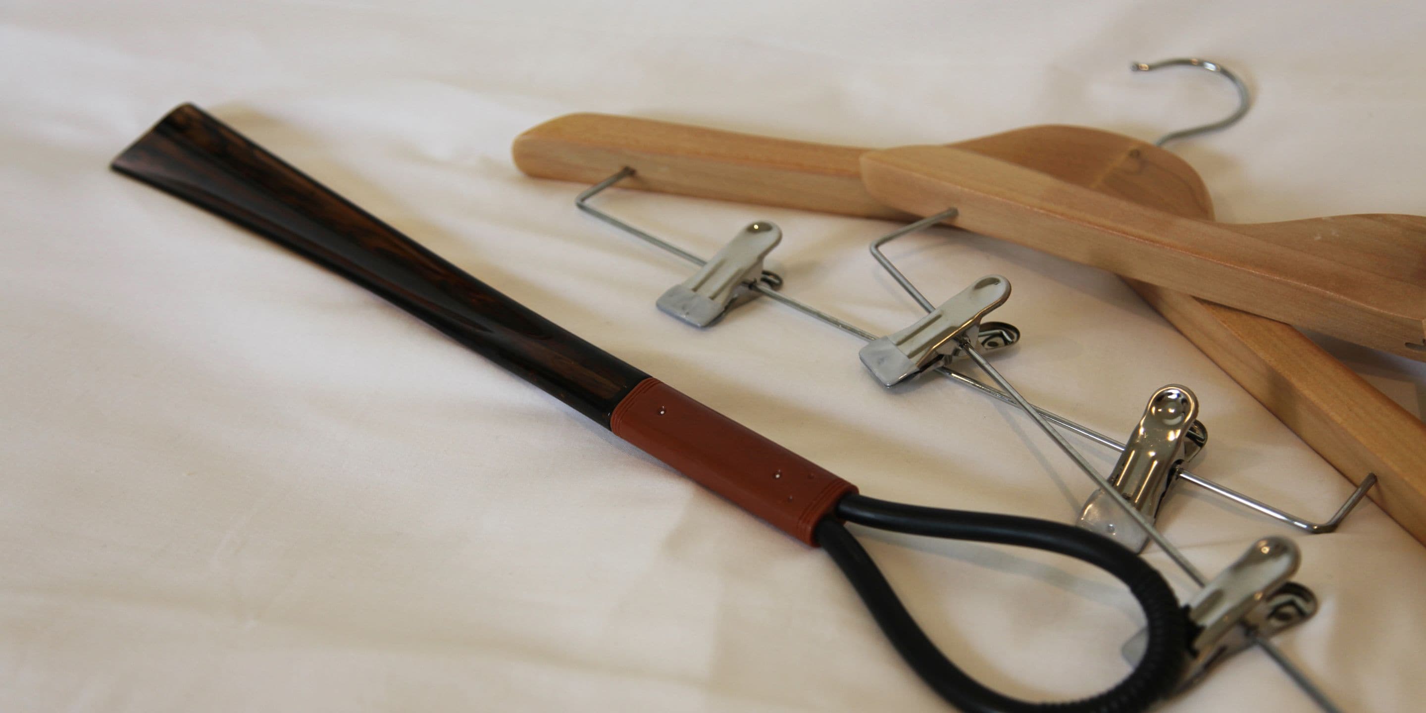 Una percha de madera con un clip metálico y una correa negra.