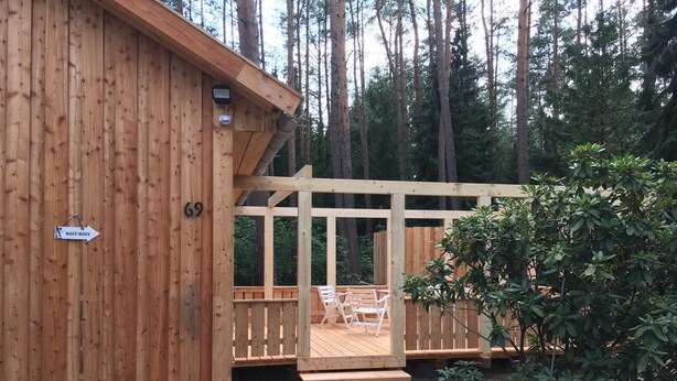 Une cabane en bois dotée d’une terrasse et d’une enseigne indiquant le numéro 69.