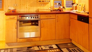 Une cuisine en bois équipée d’une cuisinière, d’un four et de meubles de rangement en bois.