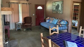 A cozy room with a wooden dining table, a sofa, and a chair. - The Sundance Cabin at the Hideaway Ranch and Refuge (Bluff Dale)