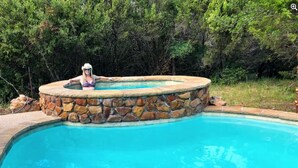 A swimming pool with a stone wall and a person in a swimsuit. - The Sundance Cabin at the Hideaway Ranch and Refuge (Bluff Dale)