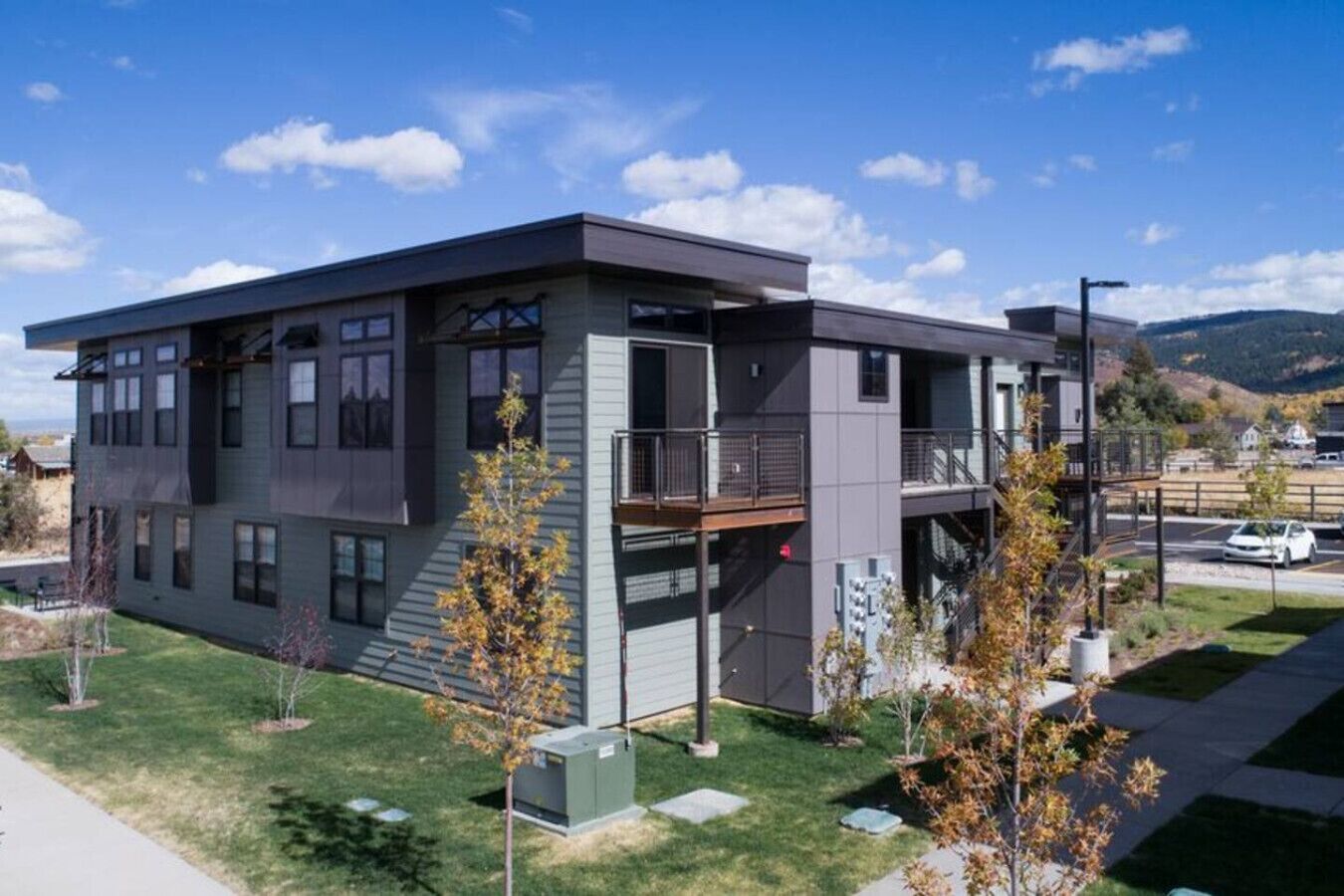 A modern two-story building with a flat roof, large windows, and a balcony.