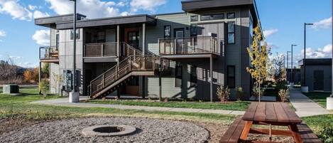 A modern building with a covered outdoor area, a staircase, and a picnic table.