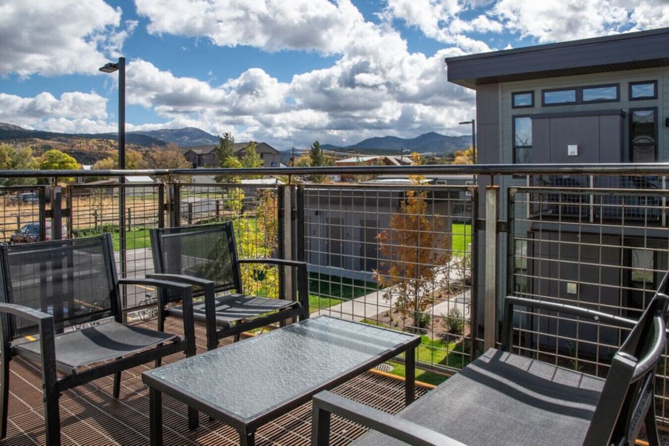 Een balkon met buitenmeubels en uitzicht op een bergachtig landschap.