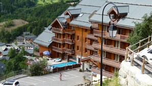 Un immeuble en bois à plusieurs étages, doté de balcons, d’une piscine et d’un espace de stationnement.