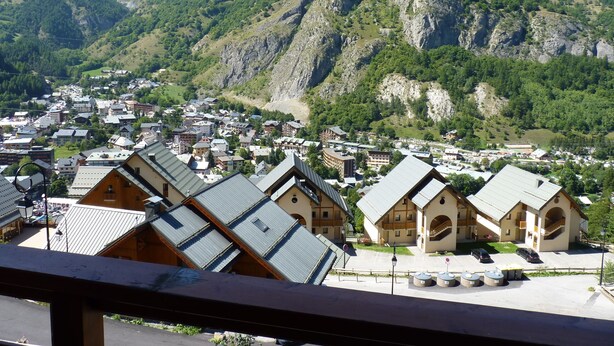 Un village de montagne aux maisons traditionnelles en bois, doté d’une place centrale et offrant une vue sur les collines environnantes.