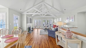A spacious living area with a wooden dining table, white chairs, a blue sofa, and a white console table with decorative items. - Neuse Village #7 - Experience your inner peace! (Arapahoe)