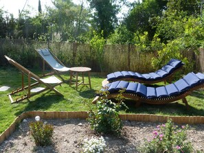 Um jardim com duas espreguiçadeiras e uma pequena mesa.