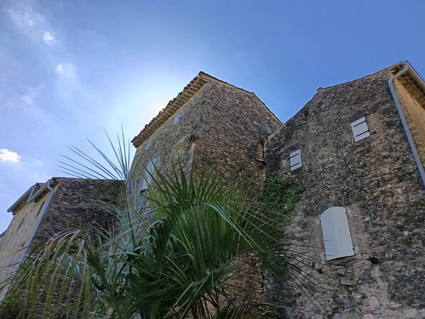 A stone building with a traditional architectural style, featuring a tiled roof and multiple windows.