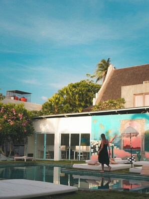 A pool area with lounge chairs and a mural. - Dream Hotel (Kuta)