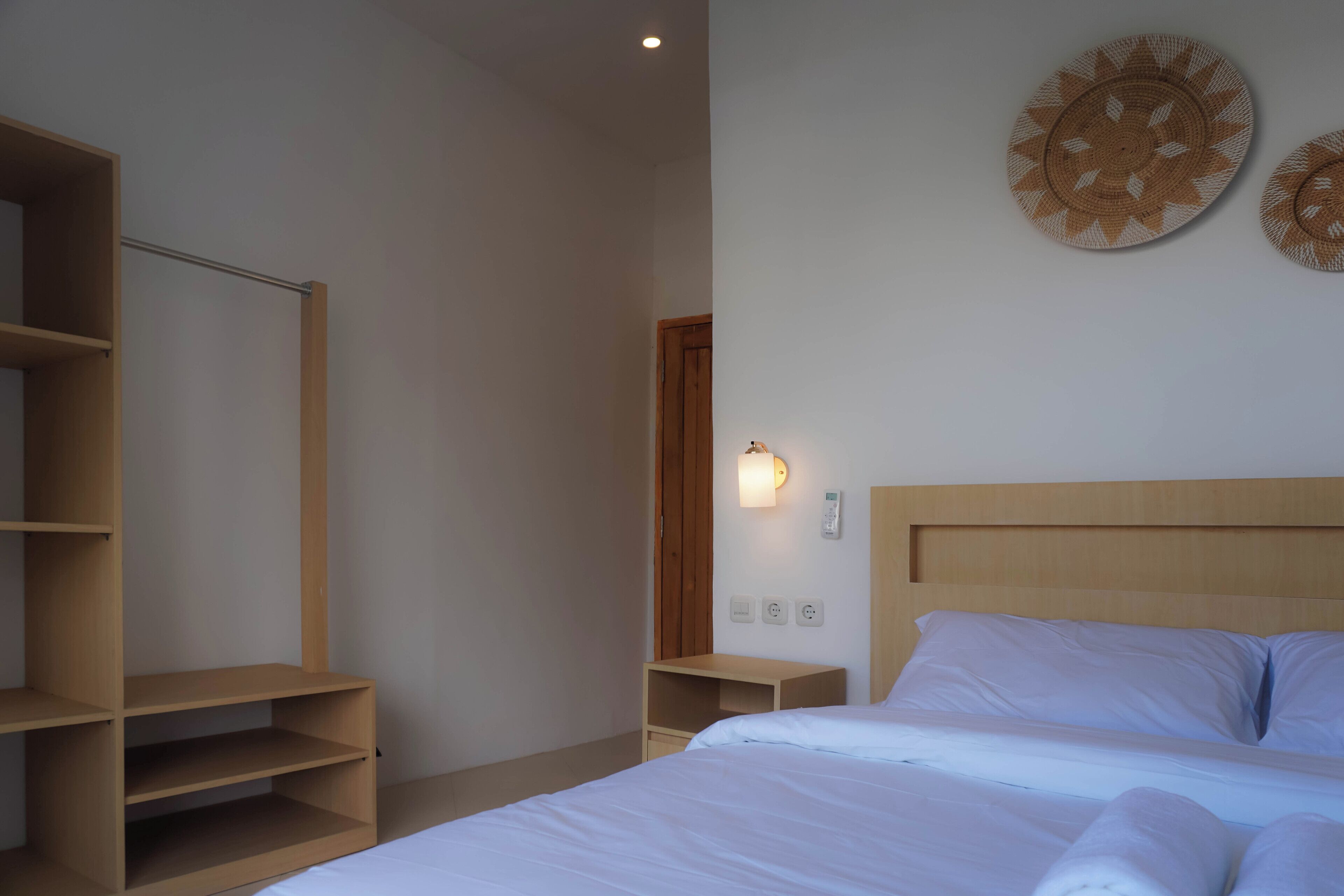 Una camera da letto con un letto, un armadio in legno, un comodino e un punto luce a parete.