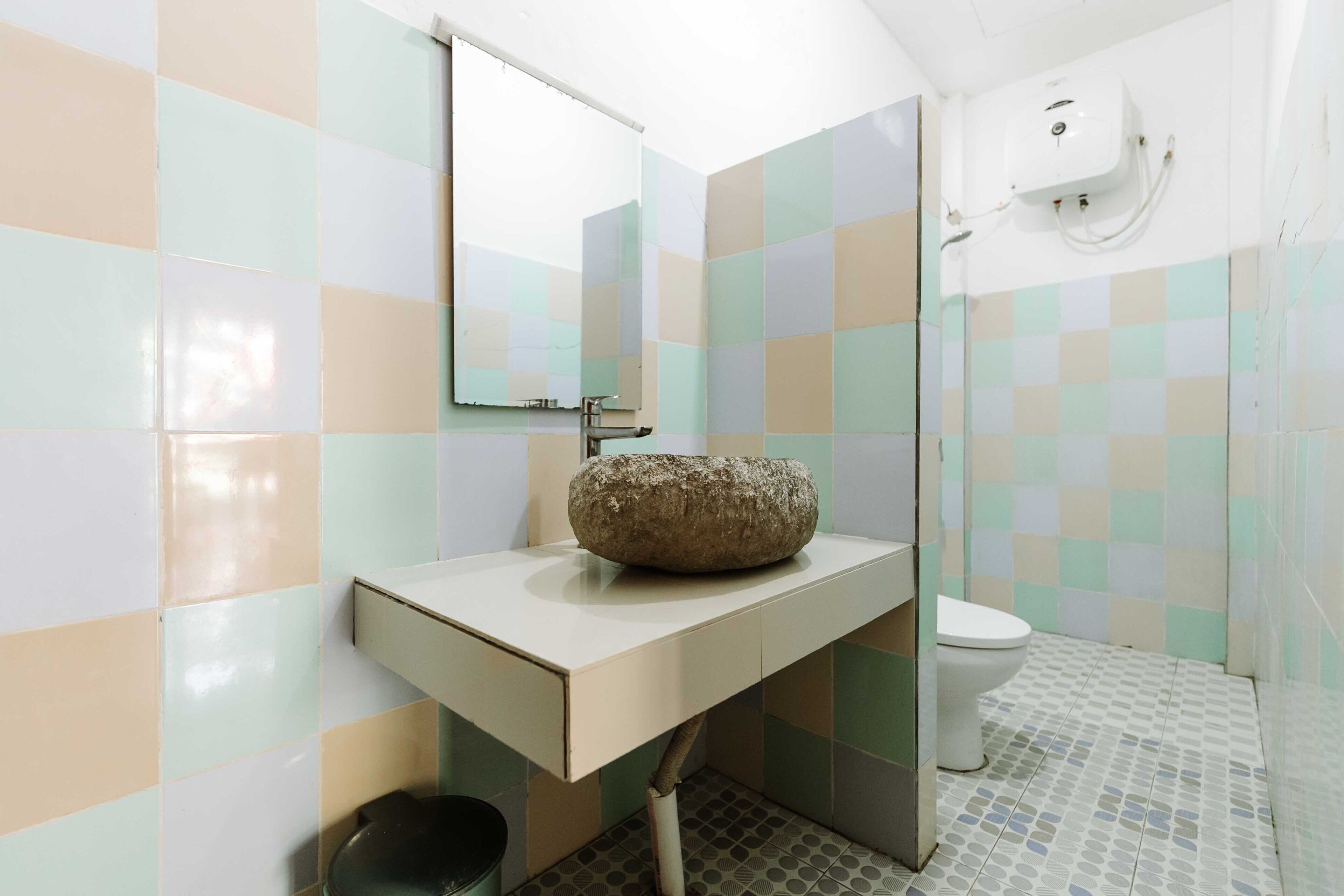 Ein Badezimmer mit Waschbecken, Spiegel, Toilette und gefliesten Wänden.