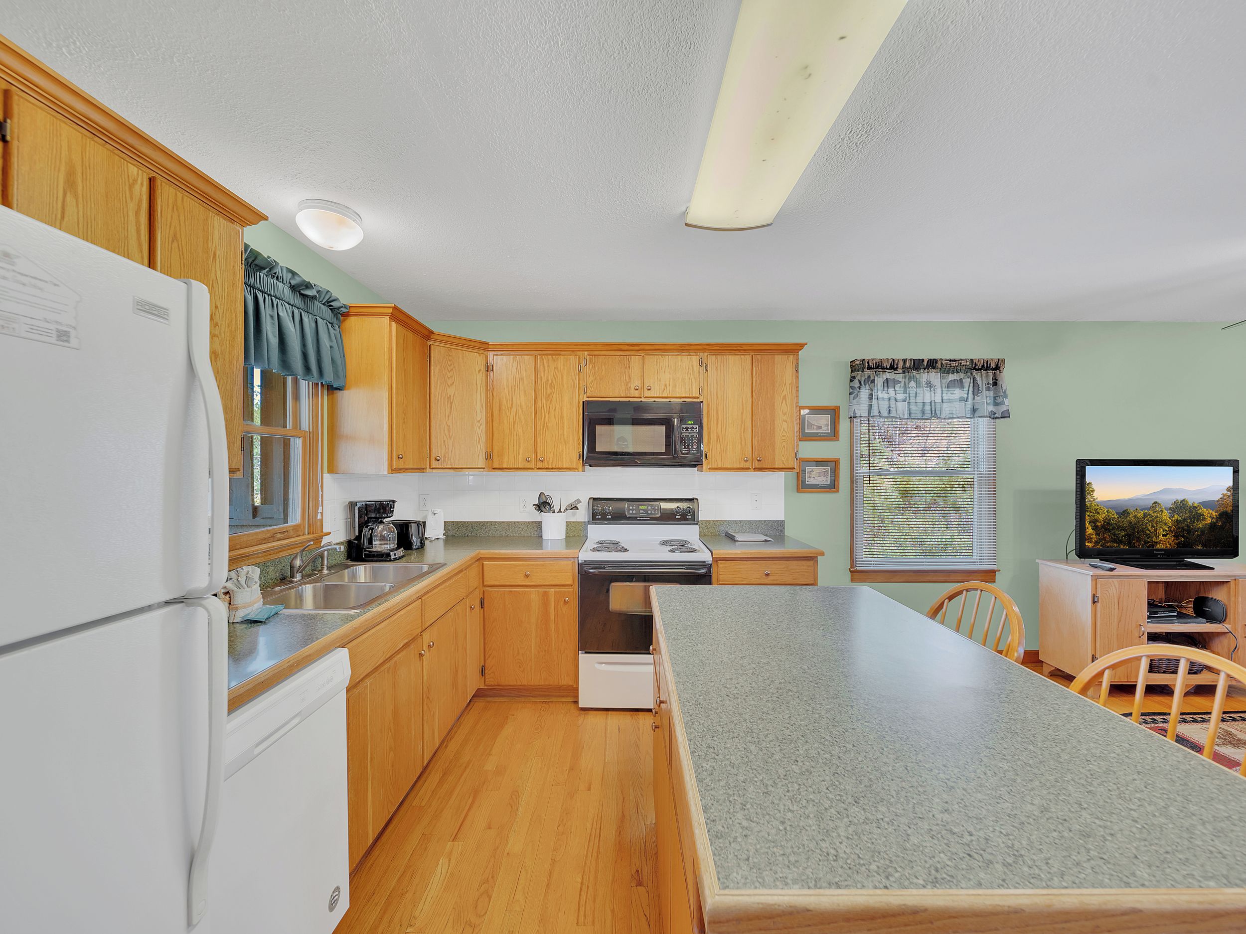 A compact kitchen with wooden cabinets, a microwave, a stove, and a sink.