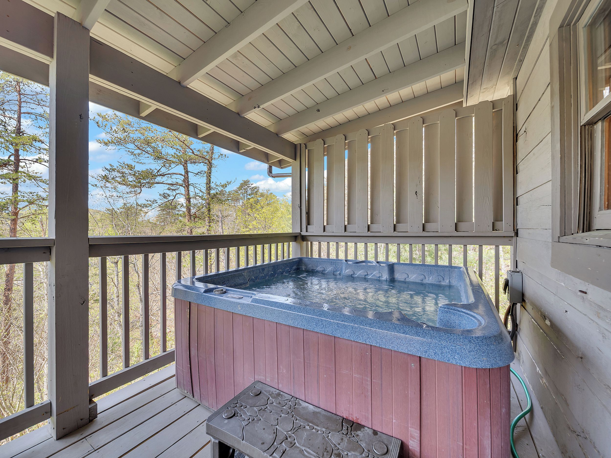 Un jacuzzi en una terraza de madera con vistas a árboles.