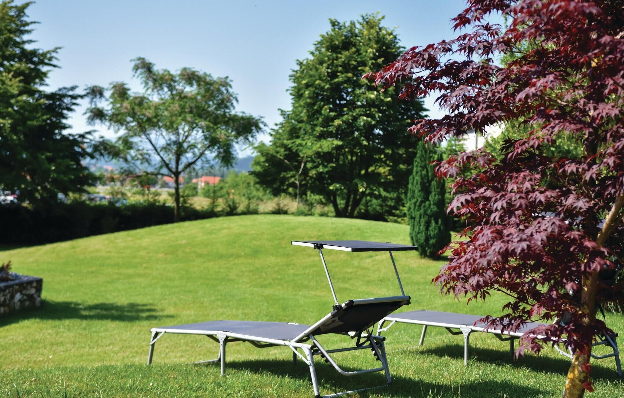 Two sun loungers with metal frames and dark cushions on a grassy lawn.