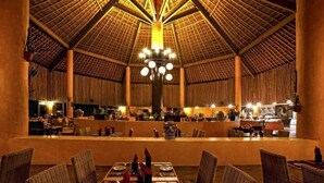 Un restaurant spacieux doté d’un haut toit de chaume et de plusieurs espaces de restauration.