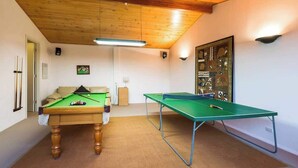 Ett rum med ett biljardbord, ett bordtennisbord och ett poolbord.