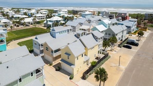 Un quartier résidentiel en bord de mer, avec des maisons dotées de balcons, offrant une vue sur la plage et s’ouvrant sur un ciel dégagé.