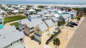 A coastal residential area with houses featuring balconies, a beach view, and a clear sky. - Sunny Side Up, Pool, Balconies & Beach Boardwalk (Port Aransas)