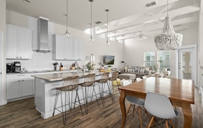 A modern kitchen with a large island, bar stools, and a dining table. - Sunny Side Up, Pool, Balconies & Beach Boardwalk (Port Aransas)