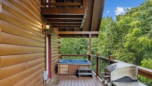 A wooden deck with a hot tub, a barbecue grill, and a wooden cabin structure. - Cozy Cabin|2 King Suites w/Jacuzzis |Near Dollywood (SEVIERVILLE)