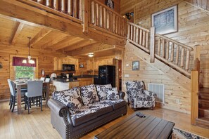 A wooden cabin interior with a dining area, sofa, and kitchen. - Cozy Cabin|2 King Suites w/Jacuzzis |Near Dollywood (SEVIERVILLE)
