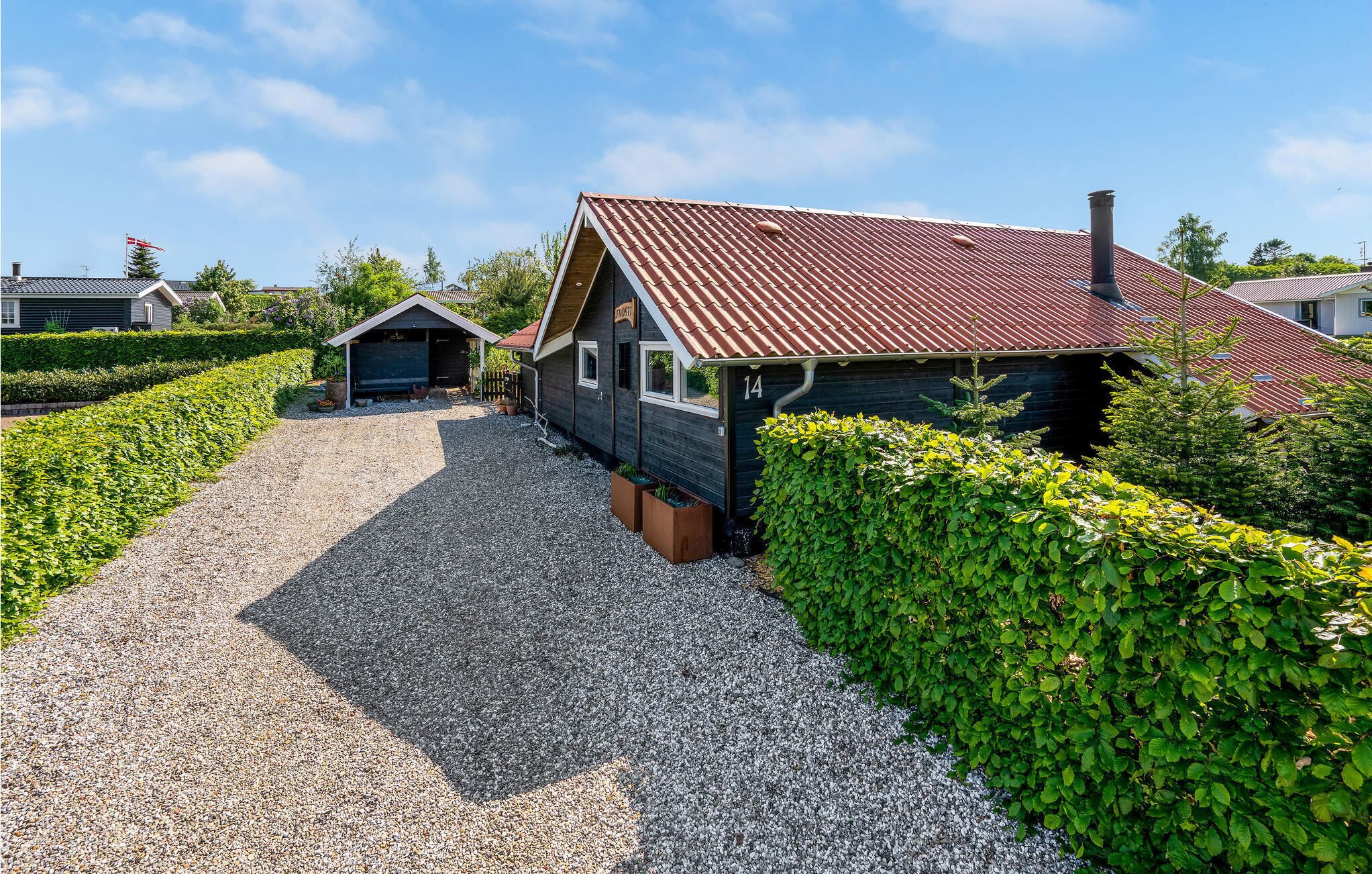 Een grindpad dat leidt naar een huis met een rode dakbedekking en een schoorsteen.