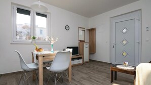Ein kompakter Wohnraum mit Essbereich, Fernseher und einer Tür mit dekorativen Rautenmustern.